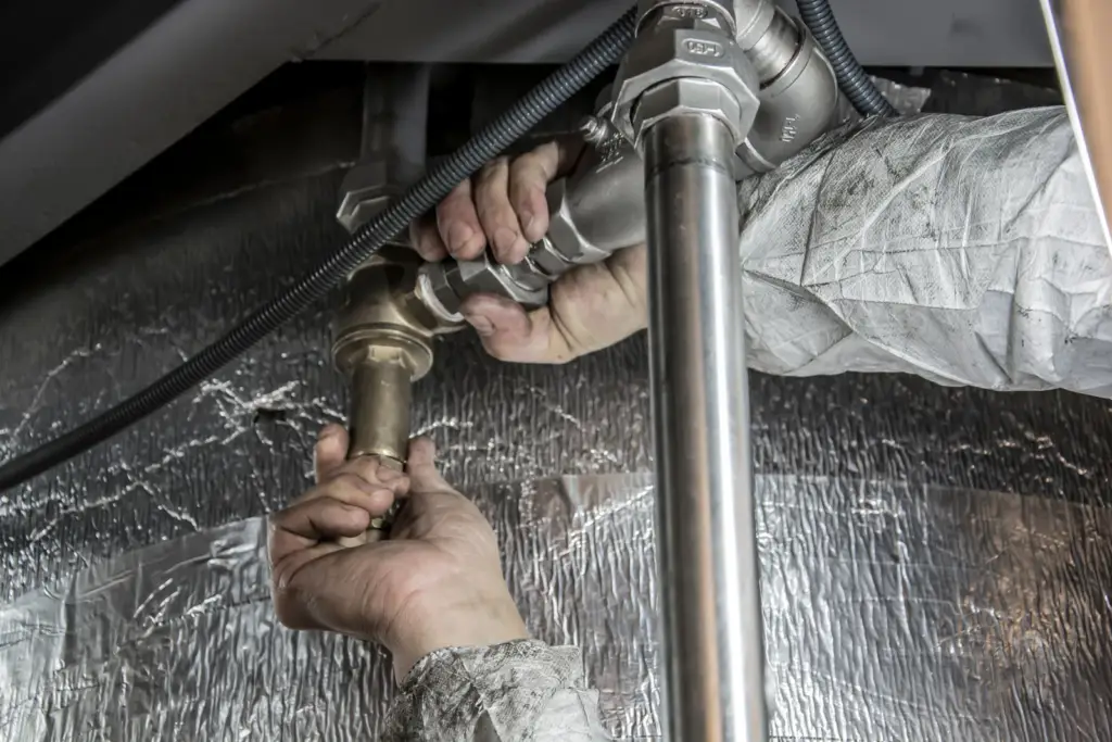 Plumber's hands fitting steel pipes with a wrench