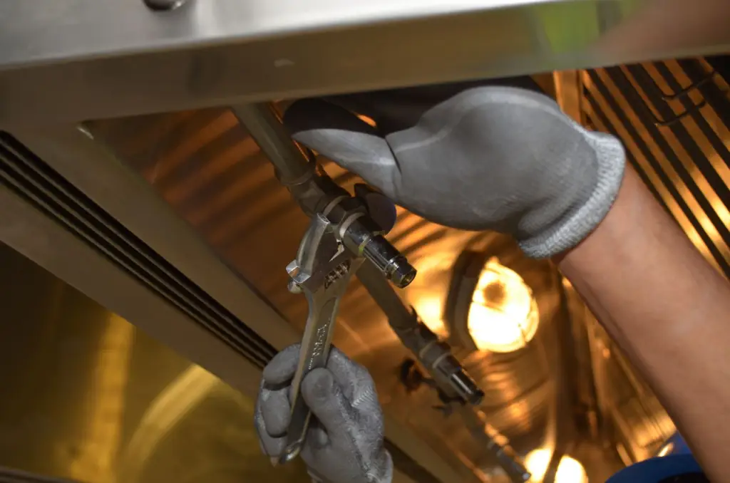 Worker tightening a pipe fitting with a wrench